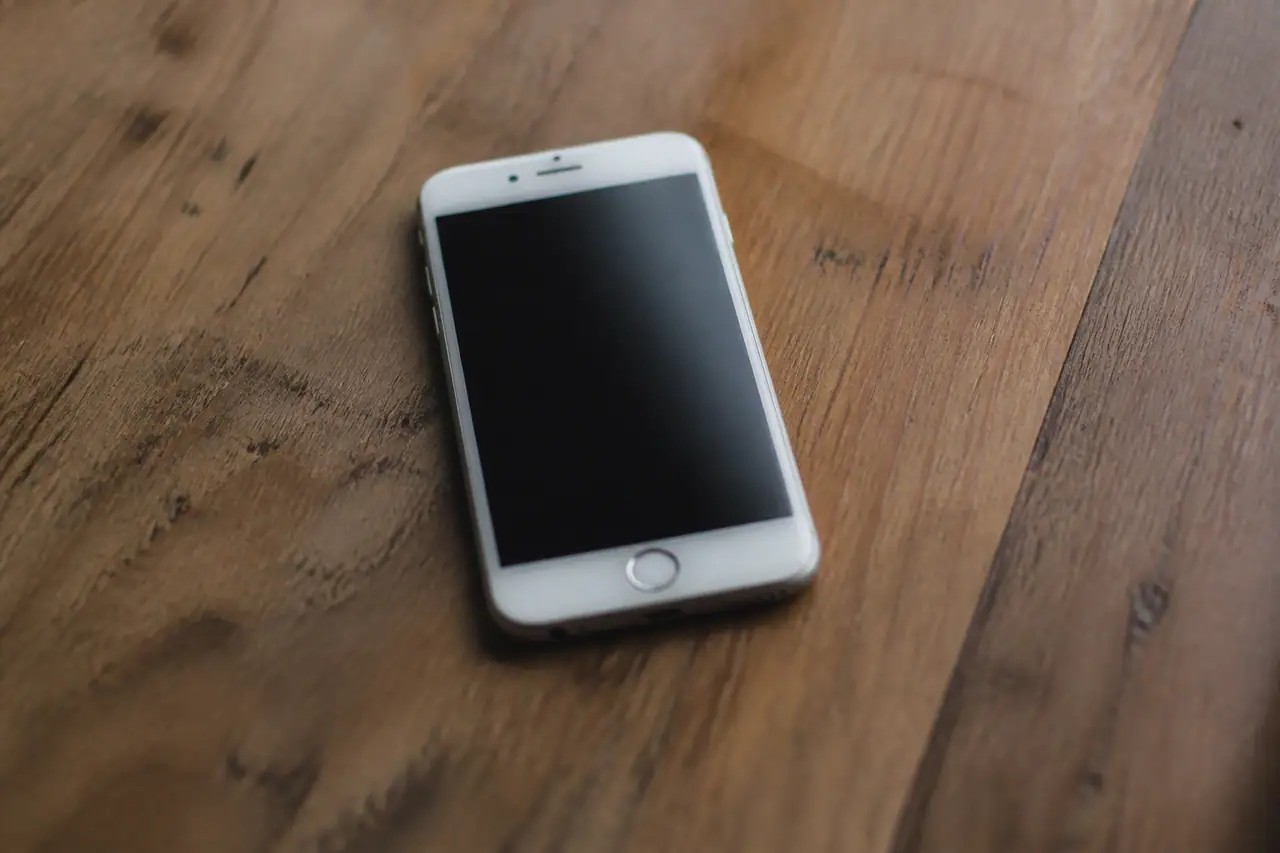 iPhone blanc sur table affichant un ecran verrouille